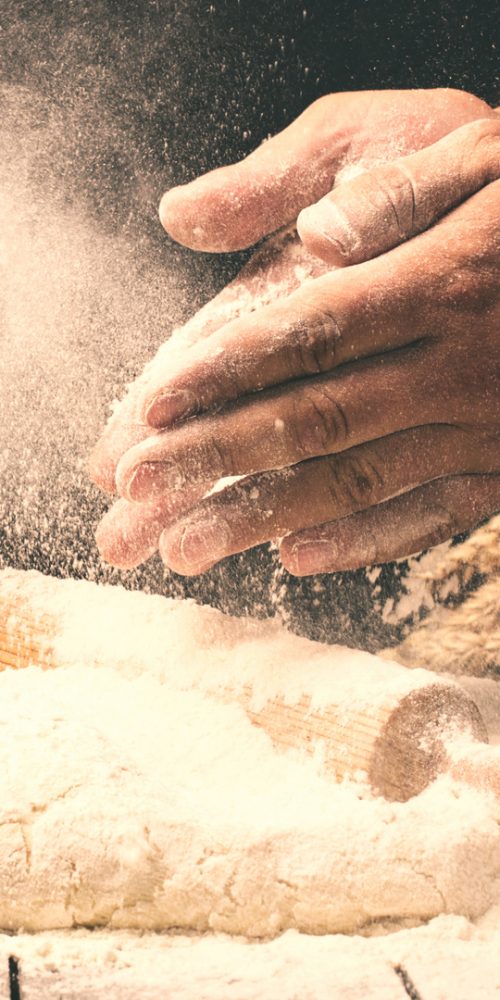 Man preparing bread dough on wooden table in a bakery Man preparing bread dough on wooden table in a bakery close up